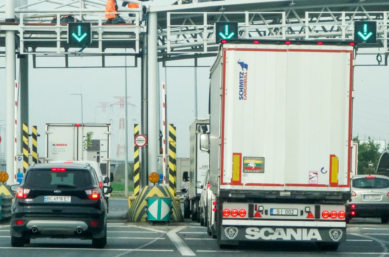 A2 pozostaje najdroższym koncesyjnym odcinkiem autostrady w Polsce, którego utrzymanie w całości finansowane jest z kieszeni kierowców. Samochód osobowy, duży samochód ciężarowy marki Scania oraz kilka innych pojazdów przejeżdżają przez stanowiska poboru opłat na autostradzie, nad jezdnią widoczne są oznaczenia świetlne ze strzałkami, na górze konstrukcji przebywają pracownicy w kamize...