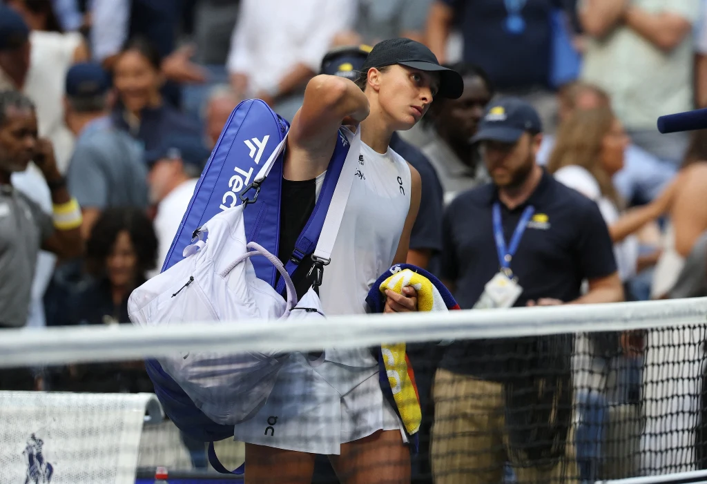 Iga Świątek pożegnała się z US Open. Jej kolejne plany wiodą przez Koreę, Chiny i Arabię Saudyjską. Aż do Polski? Tenisistka ubrana w sportową odzież z torbą na ramieniu opuszcza kort po meczu, w tle widoczni kibice i obsługa turnieju.