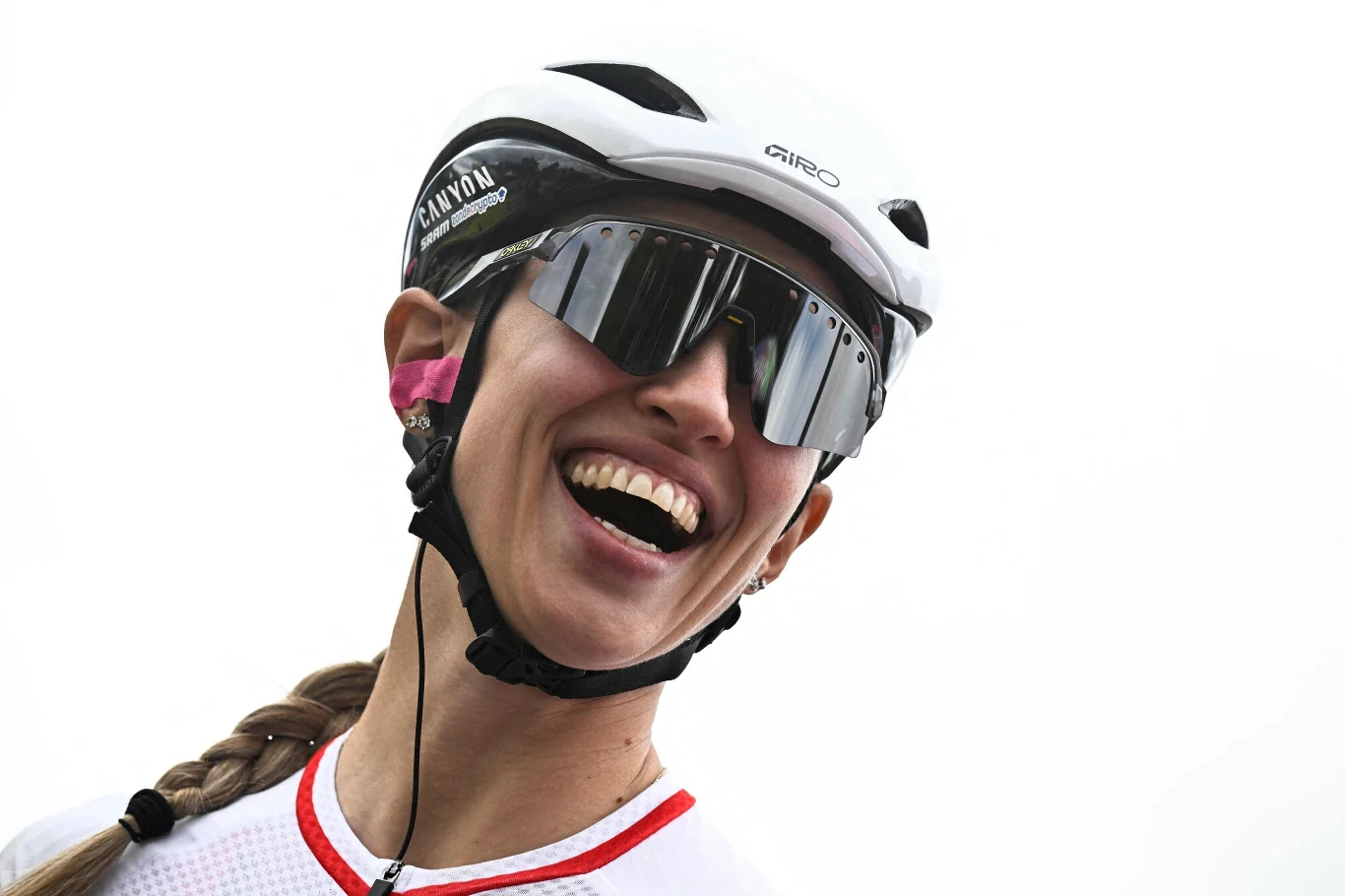 Katarzyna Niewiadoma Uśmiechnięta kobieta w sportowym stroju rowerowym, kasku oraz okularach przeciwsłonecznych, z zaplecionym warkoczem po lewej stronie.