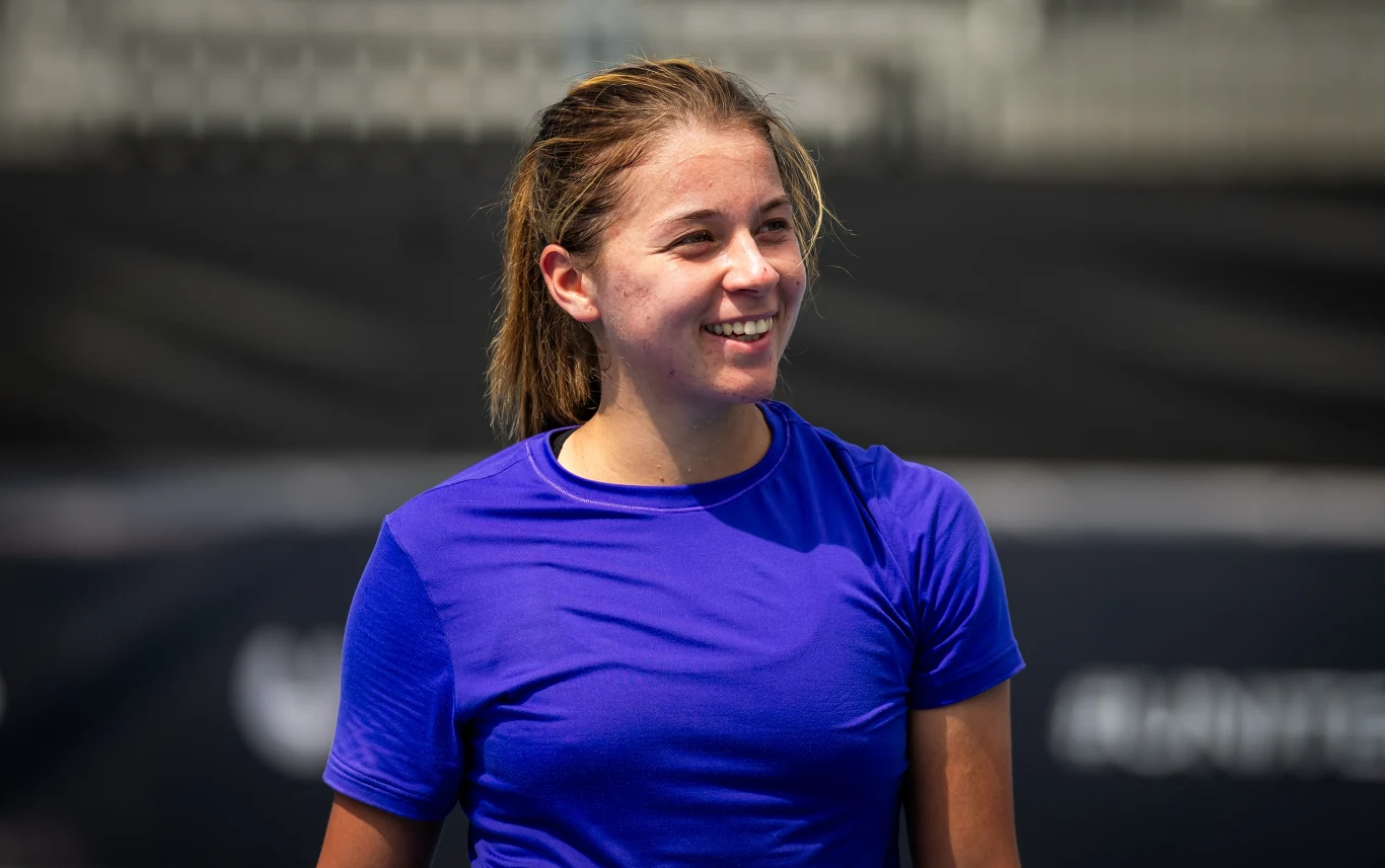Maja Chwalińska Młoda kobieta w sportowej koszulce koloru niebieskiego, uśmiechnięta, stoi na tle niewyraźnych trybun stadionowych, światło dzienne.