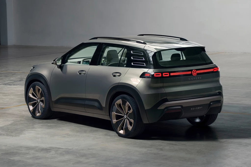 Volkswagen ID. Cross Concept Nowoczesny SUV marki Volkswagen w metalicznym kolorze szarym, stojący w przestronnym, dobrze oświetlonym pomieszczeniu, widok na tył oraz bok pojazdu z wyraźnymi detalami tylnych lamp LED i charakterystycznym logo producenta.