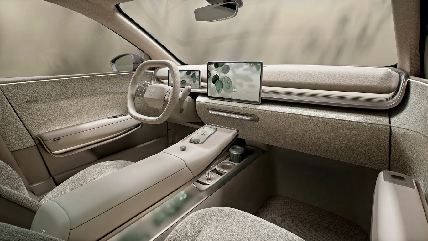 Futurystyczne, minimalistyczne wnętrze samochodu z jasną tapicerką, dużym ekranem panelu sterowania na desce rozdzielczej oraz nowoczesną kierownicą, centralny tunel wyposażony w niewielkie schowki i miejsca na kubki.