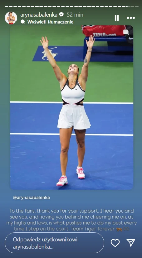 Tenisistka stojąca na korcie z uniesionymi rękami, uśmiecha się i patrzy w górę celebrując zwycięstwo, ubrana w biały strój sportowy, widoczne białe linie kortu i rakieta tenisowa poza kadrem.