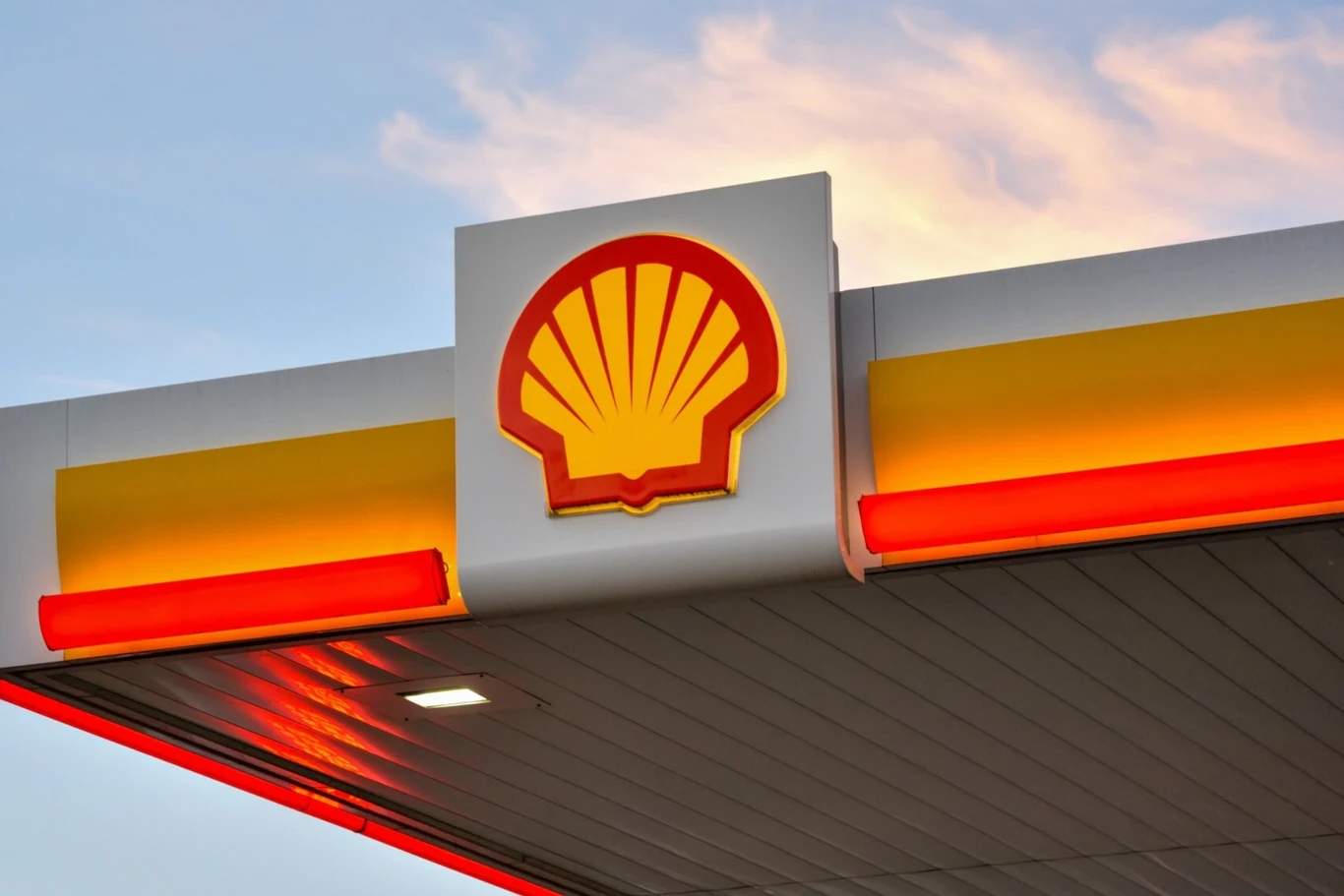 Koncerny naftowe ograniczają swoje projekty zielonej energii Logo sieci stacji paliw Shell na minimalistycznej konstrukcji dachu stacji, wyraźnie widoczne na tle jasnego nieba o zachodzie słońca