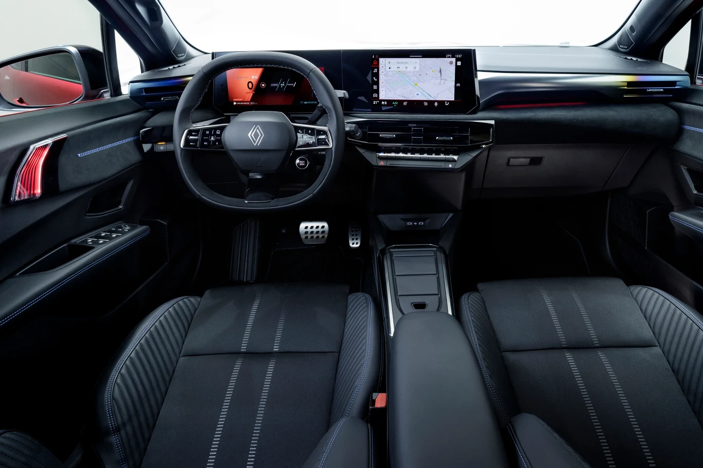 Nowoczesne wnętrze samochodu Renault z cyfrową deską rozdzielczą, dużym ekranem dotykowym na konsoli centralnej, sportową kierownicą oraz komfortowymi, czarnymi fotelami z ozdobnymi przeszyciami.