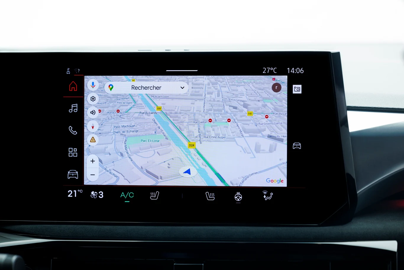Kolorowy ekran systemu nawigacji samochodowej z widoczną mapą miasta, ikonami ostrzeżeń drogowych, panelami sterowania klimatyzacją, datą, godziną oraz temperaturą powietrza.