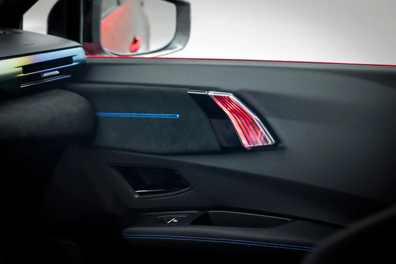 Wnętrze drzwi samochodu z widocznym nowoczesnym panelem, eleganckim wykończeniem, ozdobnymi przeszyciami oraz przyciskami sterującymi szybą.