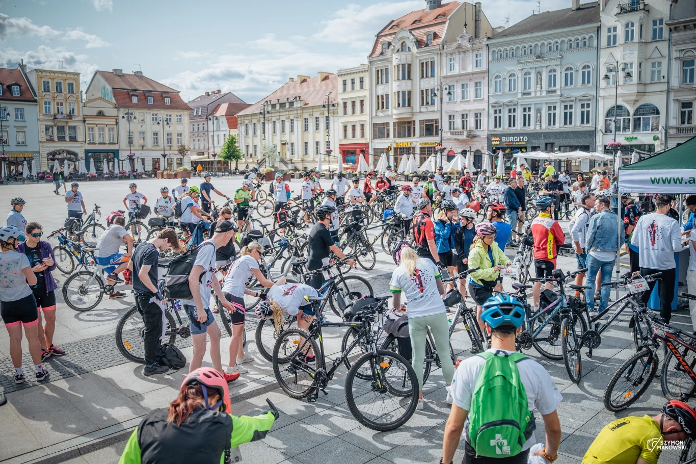 Rowery to ulubiony środek transportu mieszkańców - Fot. Miasto Bydgoszcz Tłum ludzi zgromadzonych na rowerach na dużym miejskim rynku w otoczeniu zabytkowych kamienic, uczestnicy ubrani sportowo, większość ma kaski i numerki na koszulkach, atmosfera wydarzenia masowego.