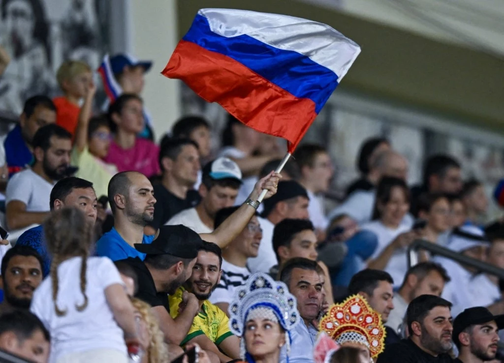 W Rosji aż huczy. FIFA miała dać zielone światło, skandal na horyzoncie Kibice na trybunach stadionu machający rosyjską flagą, wśród tłumu osoby ubrane w tradycyjne elementy folklorystyczne.