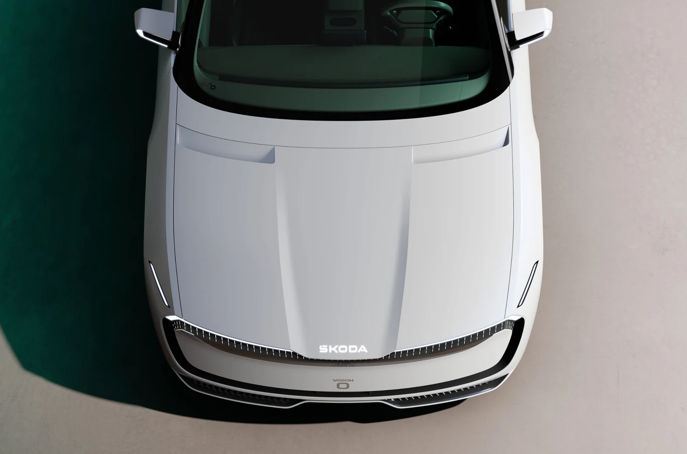 Biały samochód marki Skoda widziany z góry, z wyraźnie widoczną maską, reflektorami LED oraz logotypem marki umieszczonym centralnie na masce.