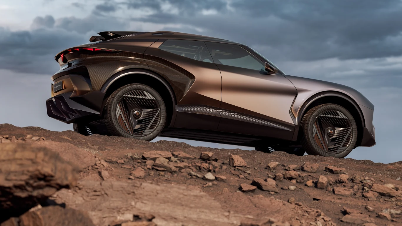 Nowoczesny samochód terenowy o futurystycznej sylwetce stoi na skalistym, pustynnym terenie przy pochmurnym niebie.