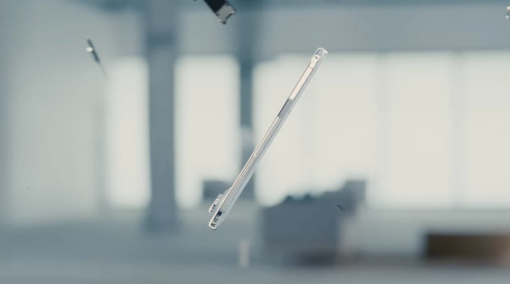 Przezroczyste etui do smartfona unoszące się w powietrzu w jasnym, minimalistycznym wnętrzu, rozmazane elementy tła podkreślają skupienie na obiekcie.