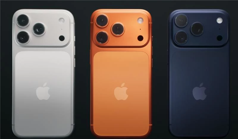 Trzy nowoczesne smartfony marki Apple w różnych kolorach: srebrnym, pomarańczowym i granatowym, ustawione obok siebie tylną stroną z wyeksponowanymi aparatami fotograficznymi.