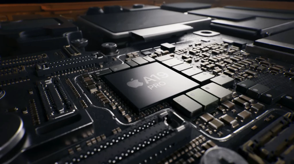 Układ scalony z centralnie umieszczonym chipem Apple A19 Pro otoczony szeregiem elementów elektronicznych na płytce drukowanej, widoczne drobne szczegóły mikroelektroniki i wyraźne oznaczenie modelu procesora.