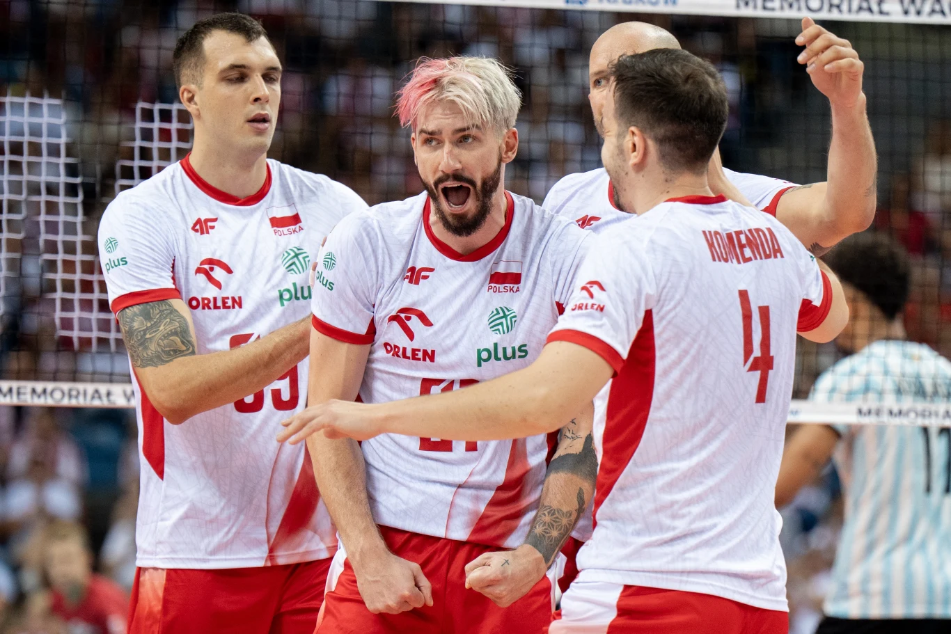 Zespół polskich siatkarzy w białych i czerwonych strojach świętuje zdobycie punktu podczas meczu, wyrażając silne emocje i sportową determinację, zawodnicy są otoczeni halą pełną widzów.