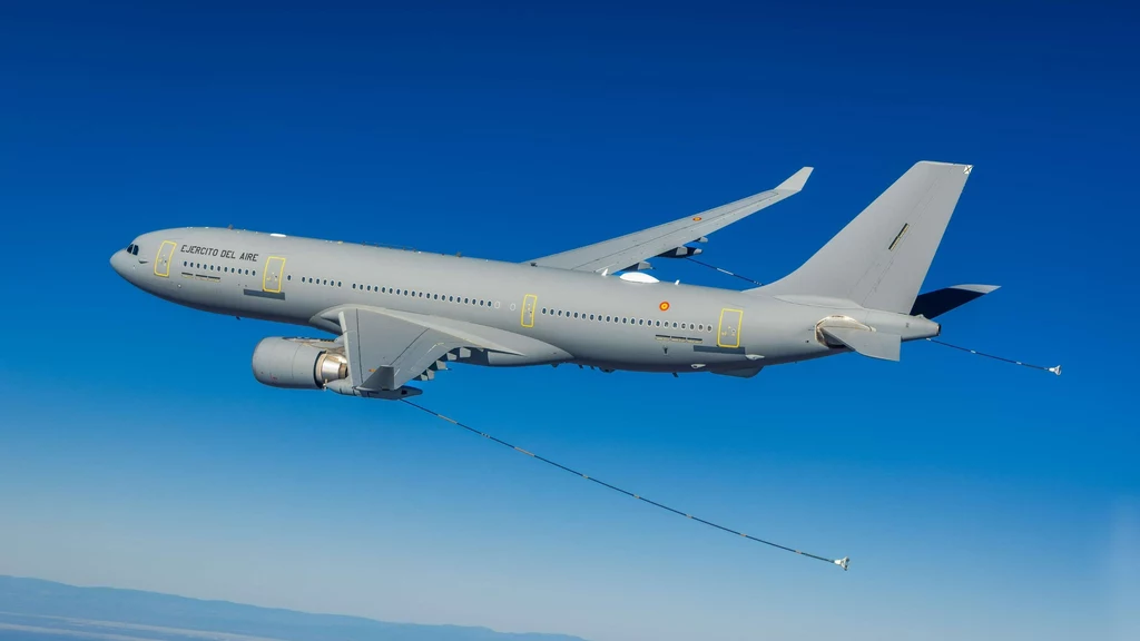 Airbus A300 MRTT Szary wojskowy samolot powietrznych sił zbrojnych z wysuniętymi przewodami tankowania, lecący na tle czystego, niebieskiego nieba.