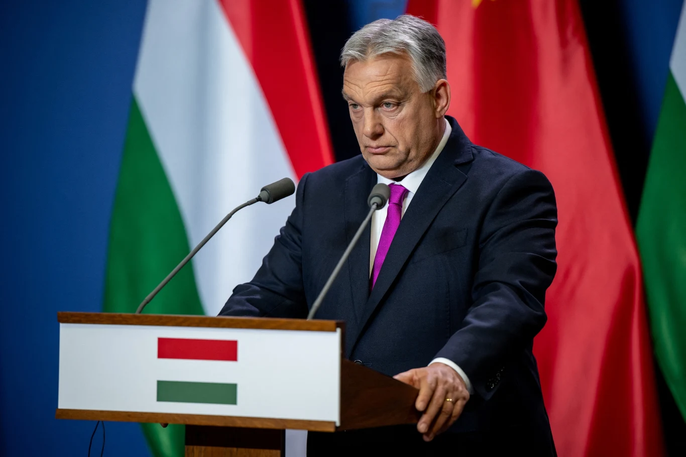 Premier Węgier Viktor Orban Mężczyzna w garniturze stoi za mównicą z flagą Węgier i Chin w tle, przemawia do mikrofonu podczas konferencji prasowej.