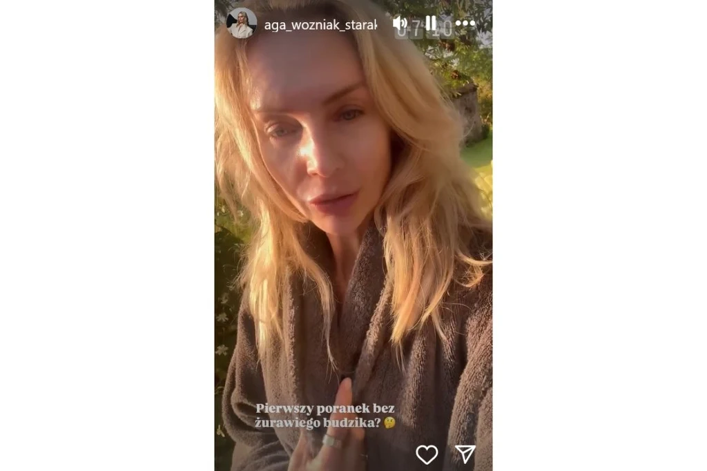 Agnieszka Woźniak-Starak bez makijażu Kobieta o blond włosach w szlafroku pozuje na zewnątrz, w porannym świetle, patrząc prosto w obiektyw. Jasne promienie słońca podkreślają jej twarz i włosy.