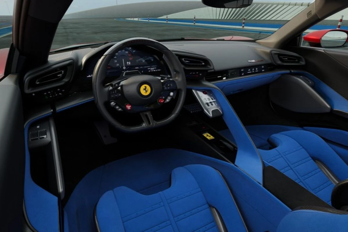 Luksusowe wnętrze sportowego samochodu z niebieskimi fotelami, dużą kierownicą z logo Ferrari oraz nowoczesną deską rozdzielczą, w tle widoczna część toru wyścigowego.