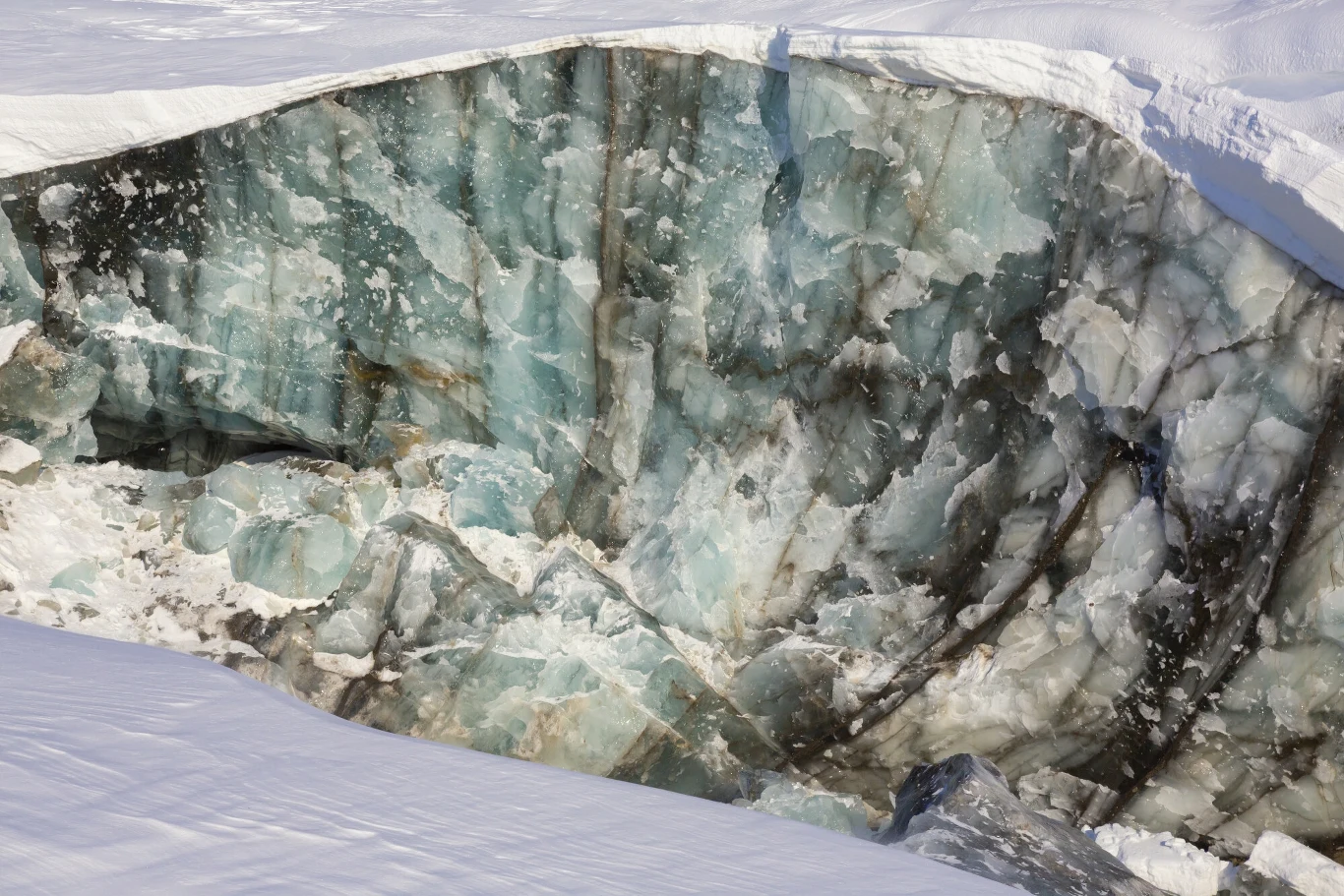 Spitsbergen to największa wyspa Norwegii, położona w archipelagu Svalbard, na Morzu Arktycznym Lodowa ściana szczeliny o złożonej strukturze z widocznymi warstwami lodu w różnych odcieniach błękitu i bieli, otoczona śniegiem.