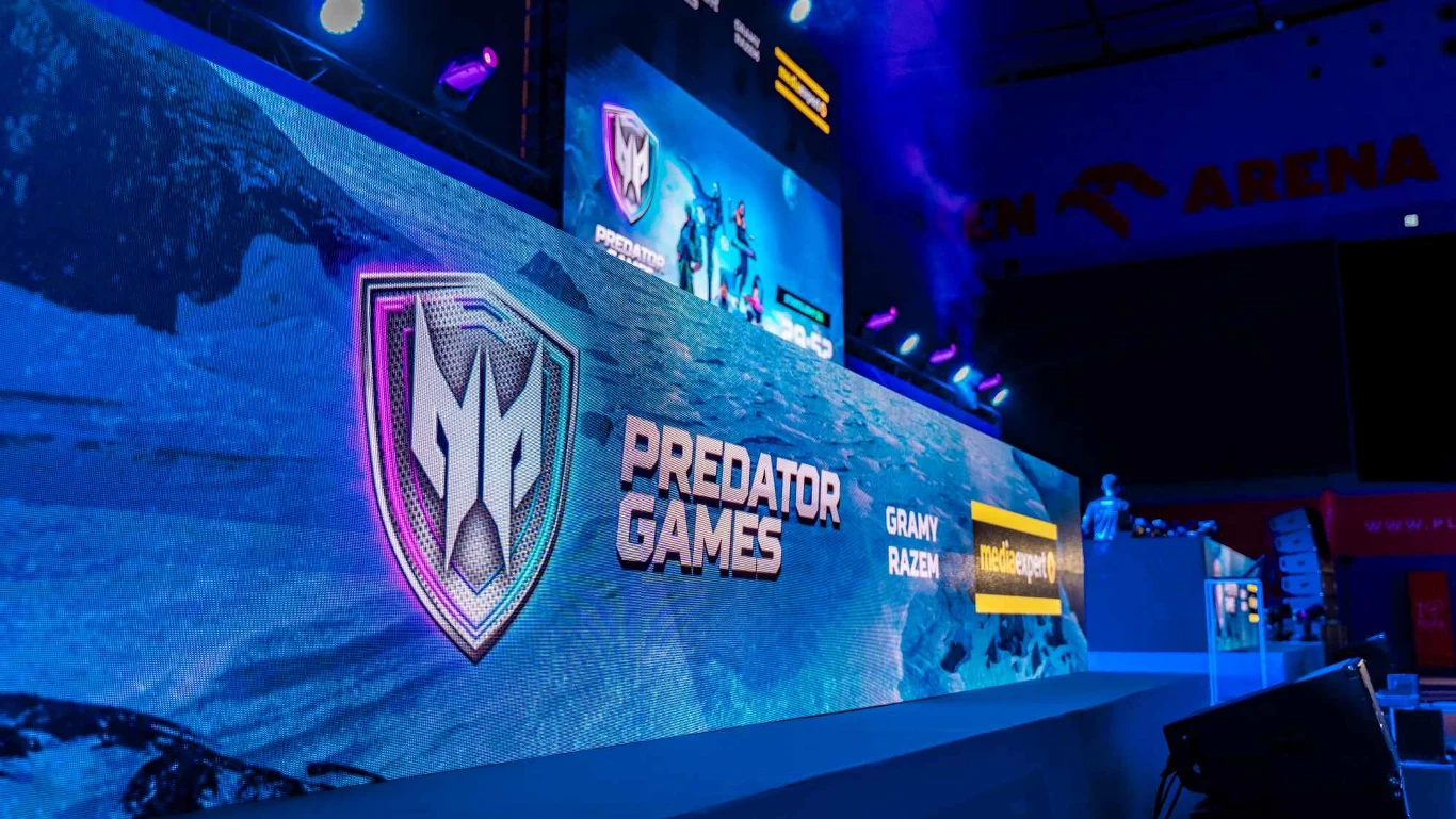 We!re Fanstasy Duży podświetlony ekran z widocznym logotypem Predator Games oraz napisami i efektami świetlnymi, scena przygotowana pod wydarzenie e-sportowe z profesjonalnym oświetleniem, widoczną częścią trybun i fragmentem areny.
