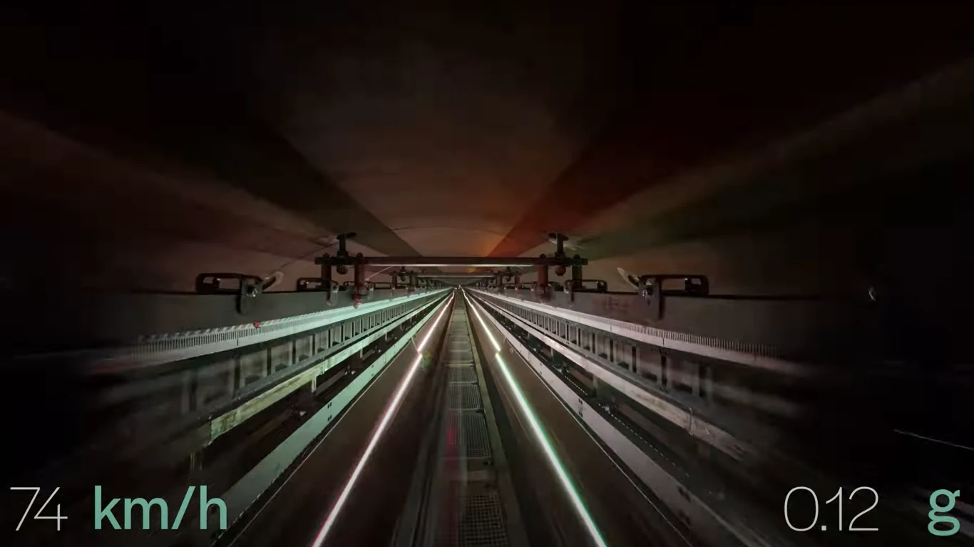 Europejski rekord hyperloop. Hardt osiąga 85 km/h i demonstruje płynną zmianę torów Widok tunelu kolejowego z dynamiczną perspektywą jazdy, po bokach widoczne szyny oraz elementy infrastruktury, w lewym dolnym rogu znajduje się prędkość 74 km/h, w prawym dolnym rogu wartość przyspieszenia 0.12 g