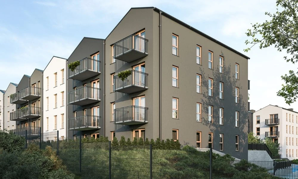 Deweloper przygotował rekomendacje z symulacją rat kredytowych Nowoczesny, kilkupiętrowy budynek mieszkalny z szarymi i białymi elewacjami, wyposażony w balkony, otoczony zielenią i metalowym ogrodzeniem, w tle kolejne podobne budynki oraz jasne niebo.