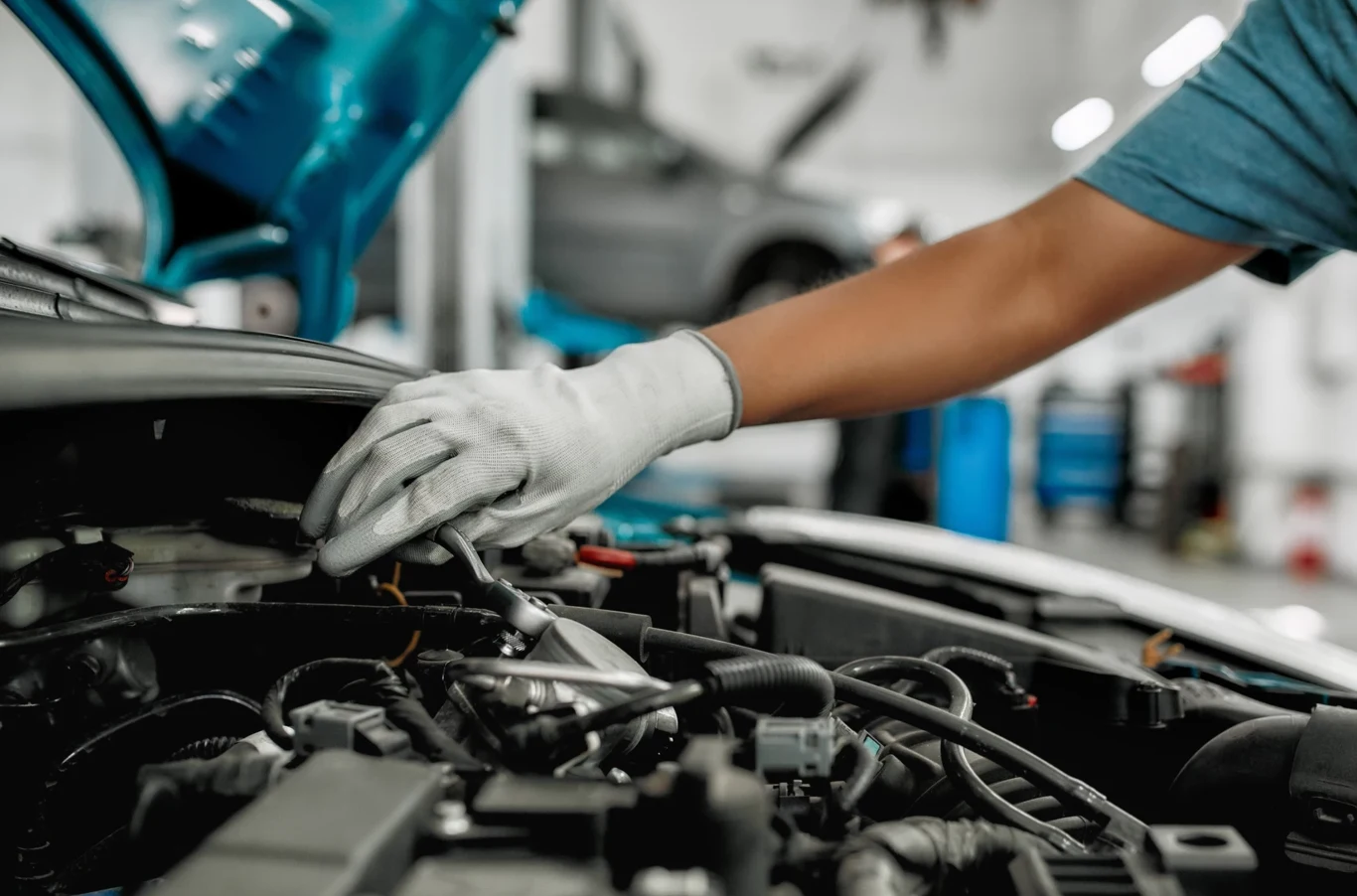 Na benzynie działa płynnie, a na gazie zaczyna szarpać. To problem znany milionom kierowców w Polsce. Mechanik w rękawiczkach naprawia silnik samochodu w warsztacie, widoczny otwarty maska i narzędzia.