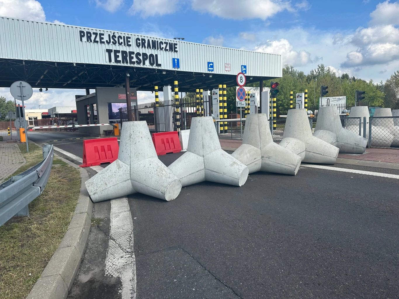 Zamknięta granica z Białorusią. Przedsiębiorcy przerażeni. MSWiA uspokaja Szlaban zamkniętego przejścia granicznego Terespol z widocznymi betonowymi zaporami przeciwczołgowymi blokującymi wjazd, na pierwszym planie asfaltowa droga, w tle zadaszona infrastruktura przejścia oraz barierki i znaki drogowe.