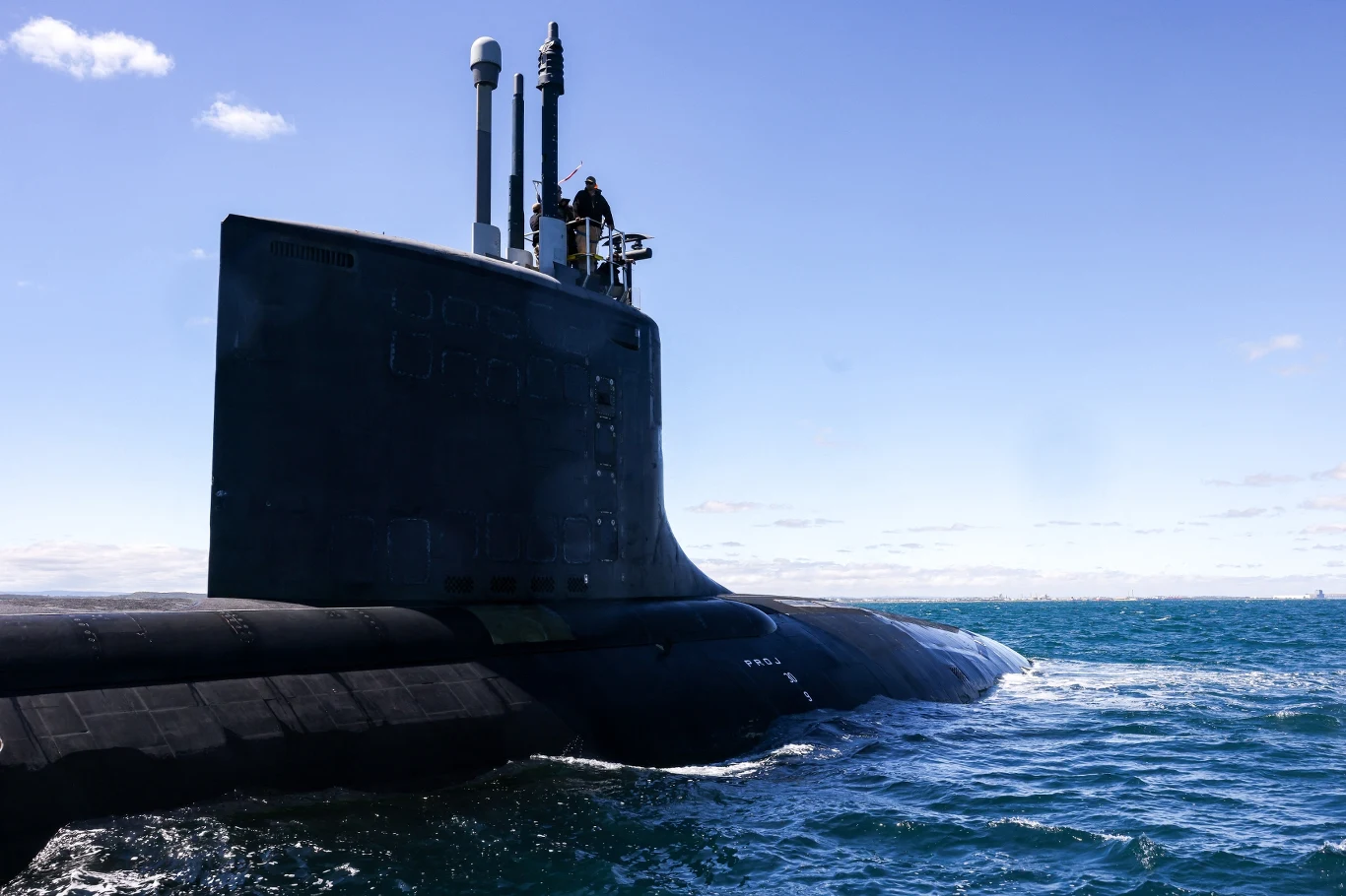 Australia inwestuje w rozbudowę stoczni, by móc obsługiwać okręty podwodne o napędzie atomowym, m.in. typu Virginia. Okręt podwodny wynurzony na powierzchni wody, z widocznym kioskiem i kilkoma osobami znajdującymi się na jego górnym pokładzie, na tle nieba i otwartego morza.