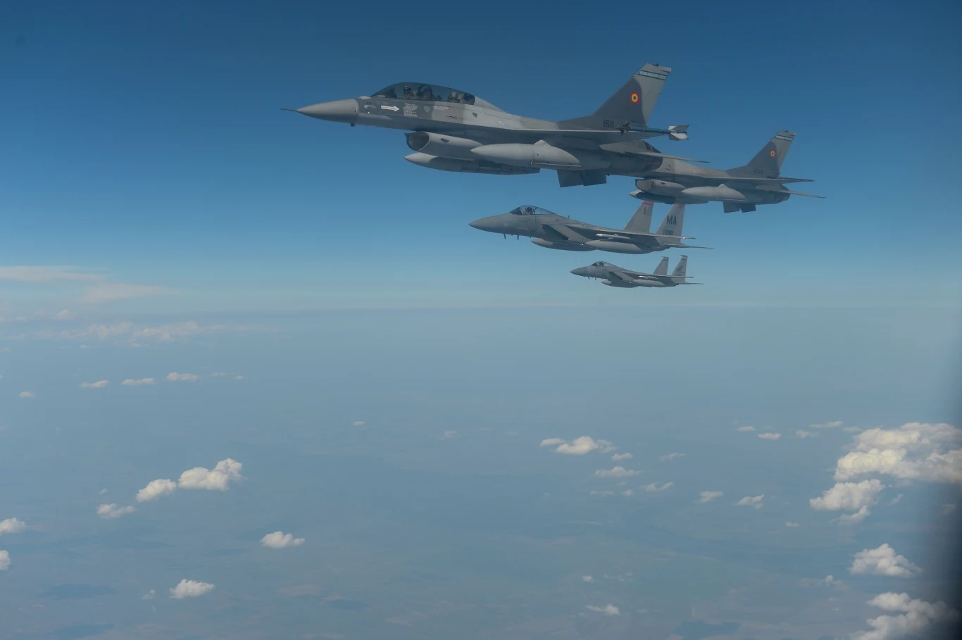 Rumunia poderwała myśliwce. F-16 przechwyciły rosyjskiego drona Cztery myśliwce wojskowe lecą równolegle na dużej wysokości nad warstwą chmur, na tle błękitnego nieba.