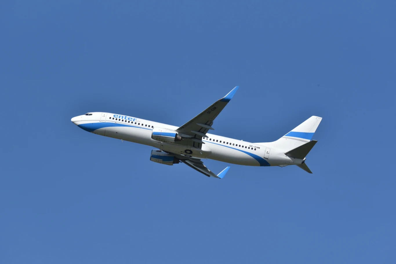 Samolot linii Enter Air. Zdjęcie ilustracyjne Duży samolot pasażerski w barwach biało-niebieskich unosi się na tle bezchmurnego, niebieskiego nieba.