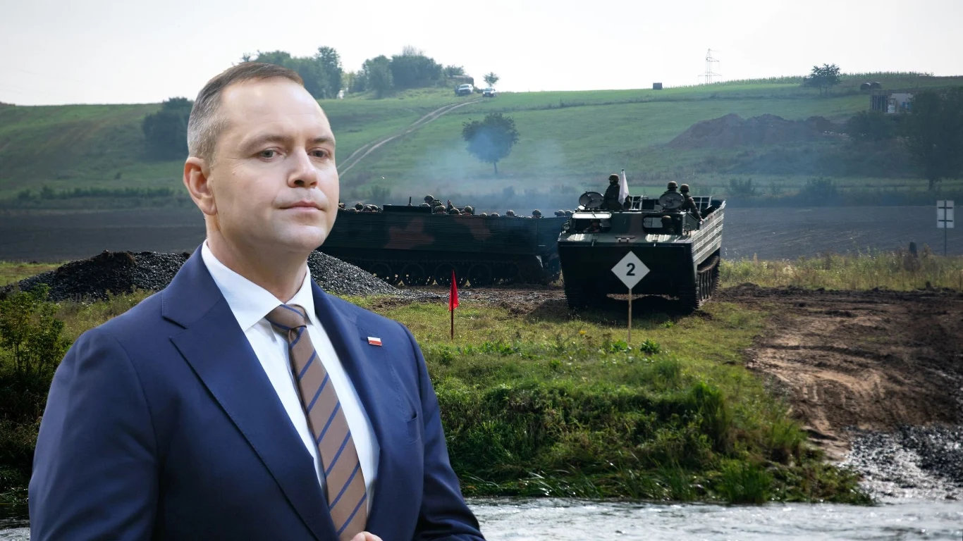 Prezydent podpisał niejawne postanowienie. Chodzi o wojska NATO w Polsce Mężczyzna w garniturze na pierwszym planie, z tyłu widoczny pojazd wojskowy oraz pagórkowaty krajobraz z zielenią i niewielkimi elementami infrastruktury.