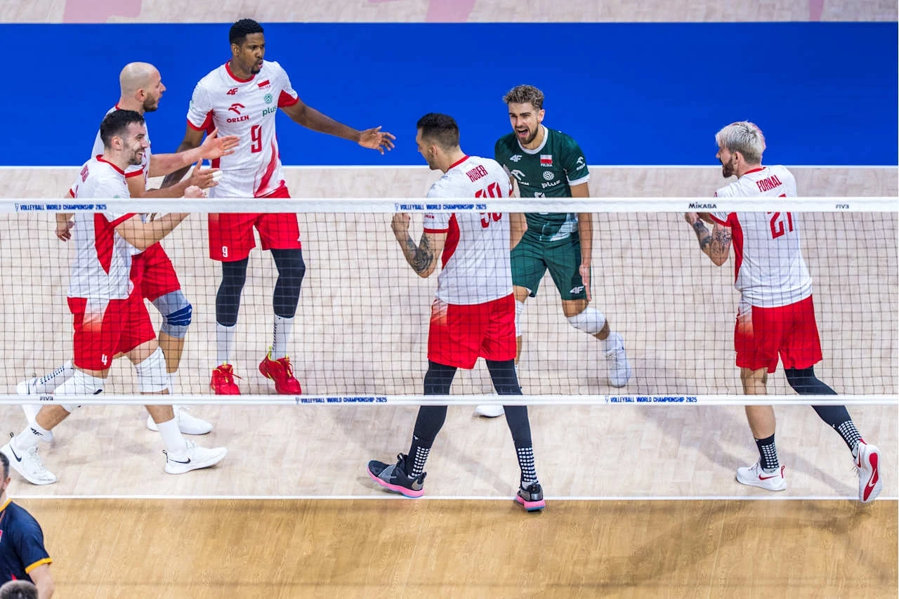 Reprezentacja Polski na MŚ 2025 na Filipinach Grupa siatkarzy w biało-czerwonych strojach oraz jeden zawodnik w zielonym stroju świętuje udaną akcję na boisku, wokół nich siatka i fragment boiska sportowego.