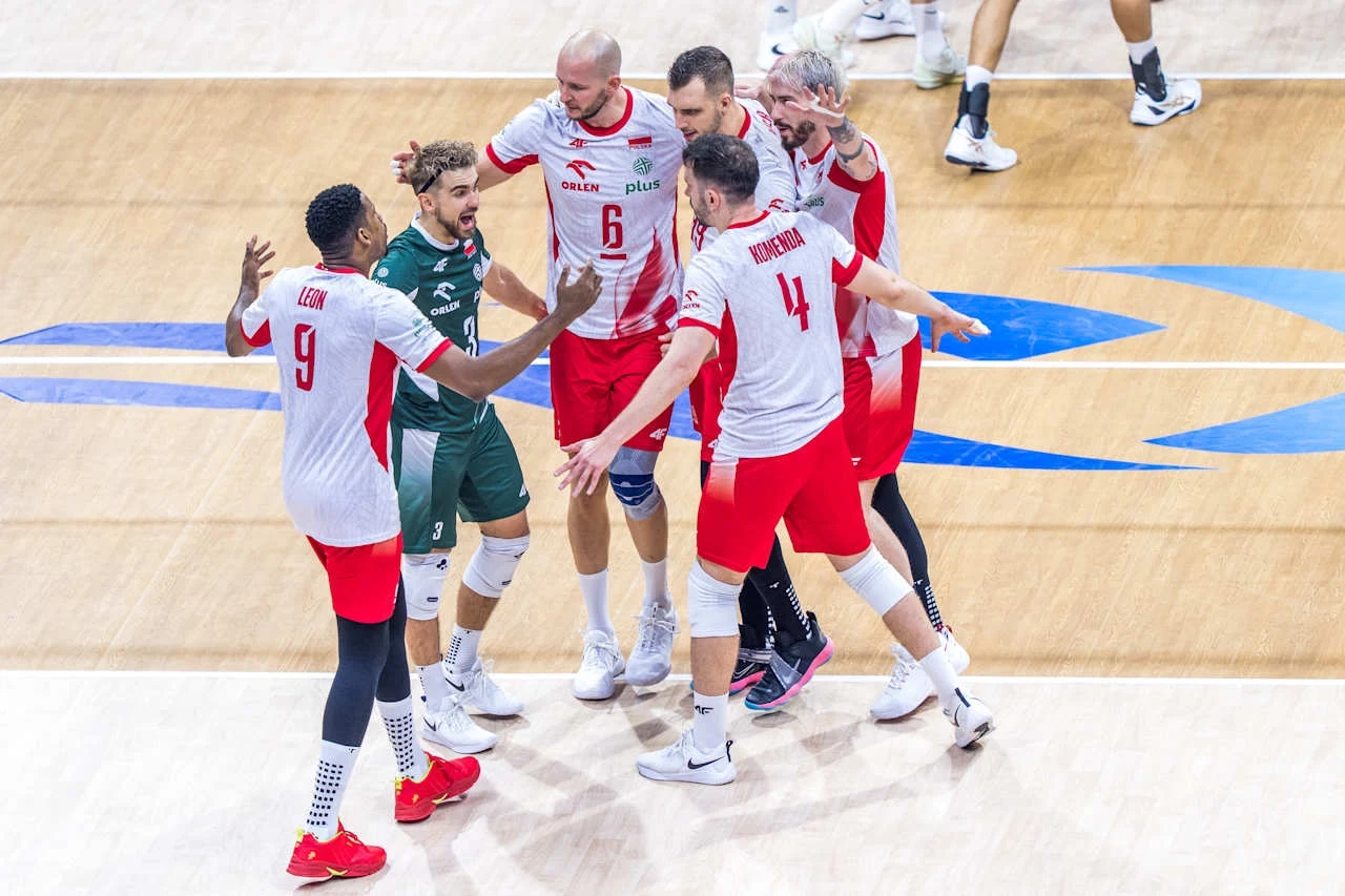 Reprezentacja Polski na MŚ 2025 na Filipinach Grupa siatkarzy w białych i czerwonych strojach świętuje zdobycie punktu na boisku podczas meczu, wykazując radość i integrację zespołową.