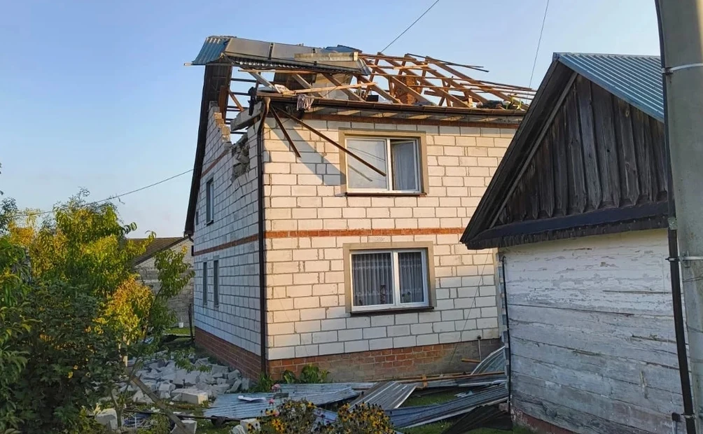 Dom w woj. lubelskim, który został uszkodzony przez niezidentyfikowany obiekt Dwukondygnacyjny dom z uszkodzonym dachem, którego część została zerwana, a fragmenty konstrukcji spadły na ziemię wokół budynku; po prawej stronie widoczny mniejszy budynek gospodarczy, na pierwszym planie leżące blachy i elementy dachu.