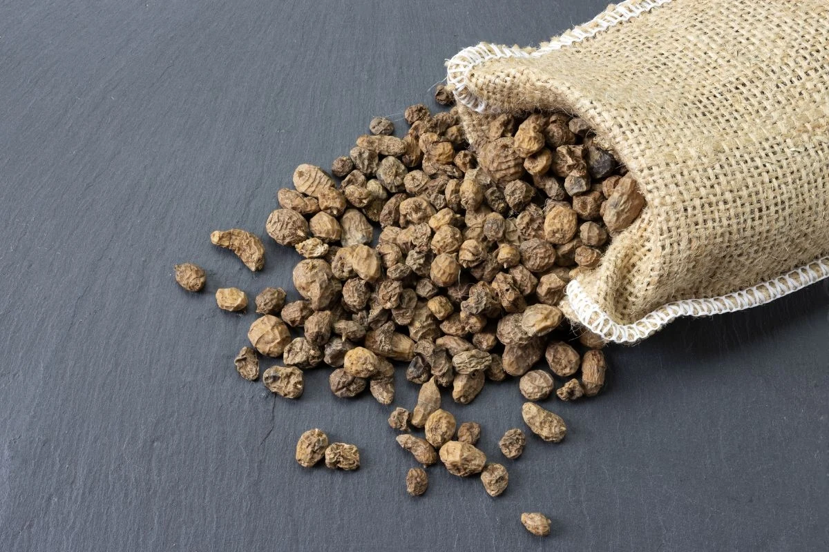 Brązowe bulwki wylewające się z jutowego worka na ciemną, gładką powierzchnię