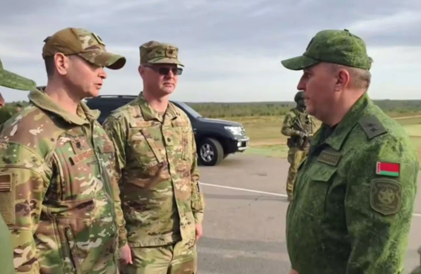 Amerykańscy oficerowie na manewrach Zapad-2025 Trzech żołnierzy w mundurach wojskowych różnych formacji prowadzi rozmowę na otwartym terenie, w tle widoczny samochód terenowy oraz kolejni żołnierze.