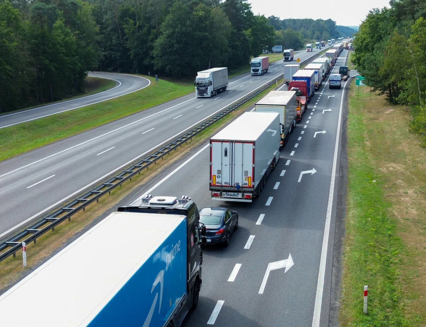 Polskie hity eksportowe to silniki odrzutowe i drób Korek na autostradzie utworzony przez liczne ciężarówki oraz samochody osobowe, obok widoczna równoległa jezdnia bez zatoru, całość otoczona lasem i zielenią.
