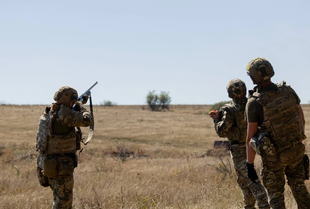 Ukraina strzela do rosyjskich dronów z karabinów i dział przeciwlotniczych, UE używa drogich rakiet. "Financial Times" pisze o "krytycznej luce". Zdj. ilustracyjne Trzech żołnierzy w pełnym umundurowaniu wojskowym stoi na suchym, otwartym polu; jeden z nich korzysta z lornetki lub urządzenia optycznego, pozostali obserwują teren, tło stanowi pusta przestrzeń w krajobrazie stepowym.