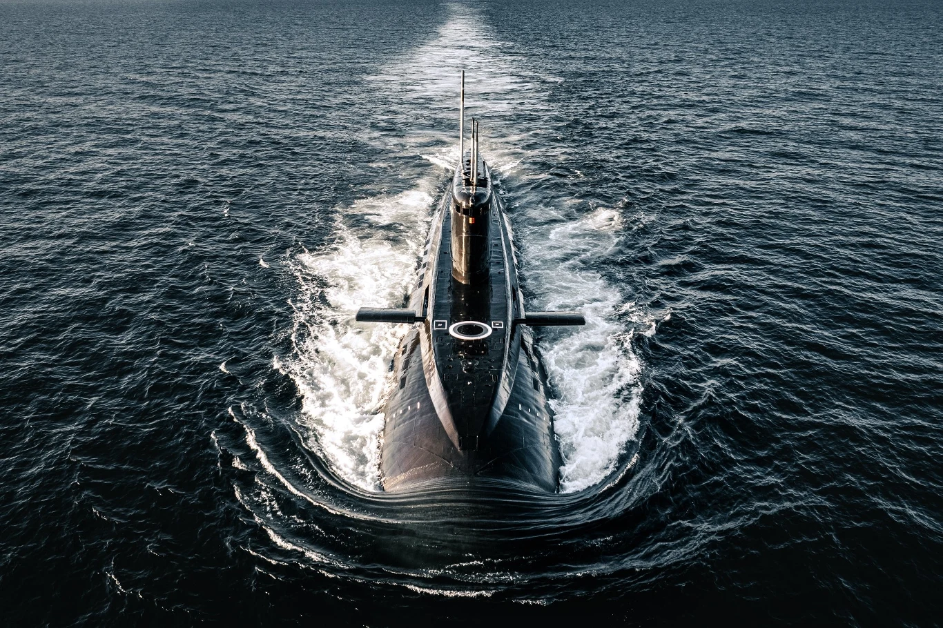 ORP Orzeł. Obecnie to najdłużej pozostający w aktywnej służbie niezmodernizowany okręt podwodny klasy Kilo Okręt podwodny płynący po powierzchni morza, widoczny ślad wody powstały w wyniku ruchu jednostki, otoczenie stanowi rozległy akwen wodny.