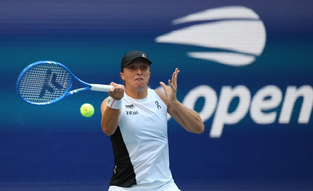 Tenisistka wykonuje dynamiczny forehand na korcie, w tle widoczne niebieskie tło z logotypem US Open