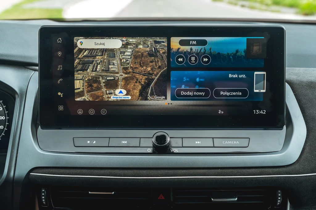 Pokładowy system oparto o Android Automotive, co daje dostęp do usług Google Duży dotykowy ekran nawigacji samochodowej z wyświetlaną mapą miasta po lewej stronie i interfejsem radia oraz opcjami połączeń po prawej stronie, otoczony panelem z przyciskami funkcyjnymi pod ekranem.