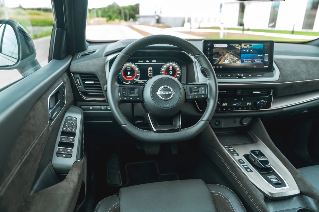 Ekrany Nissana Qashqai mają po 12,3 cala wielkości. Uzupełnia je opcjonalny wyświetlacz HUD Nowoczesne wnętrze samochodu Nissan z widocznym kierownicą, cyfrowym zestawem wskaźników, dużym ekranem systemu multimedialnego oraz panelem sterowania na konsoli środkowej.
