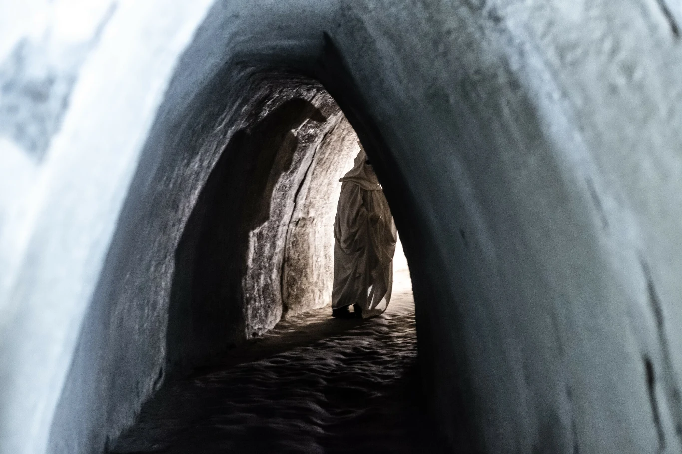 W tunelach kopalni można spotkać ducha Ciemny tunel skalny z osobą w białym stroju idącą w kierunku światła na końcu korytarza, wywołujący efekt tajemniczości i skupienia na postaci.