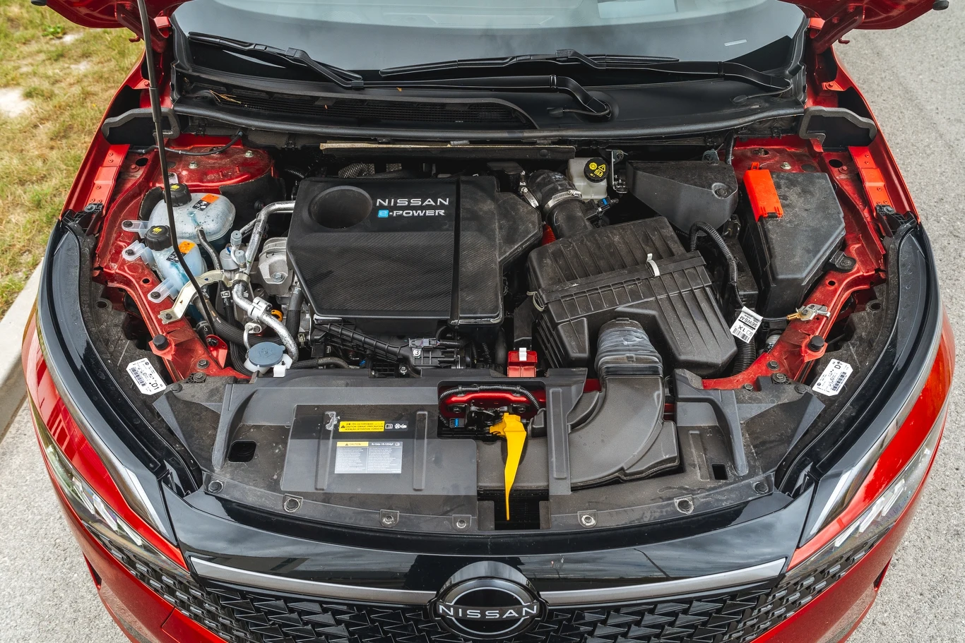 Komora silnika samochodu Nissan z widocznym układem e-POWER, akumulatorem i komponentami mechanicznymi, utrzymana w czystości i dobrym stanie technicznym, sfotografowana od góry przy otwartej masce.