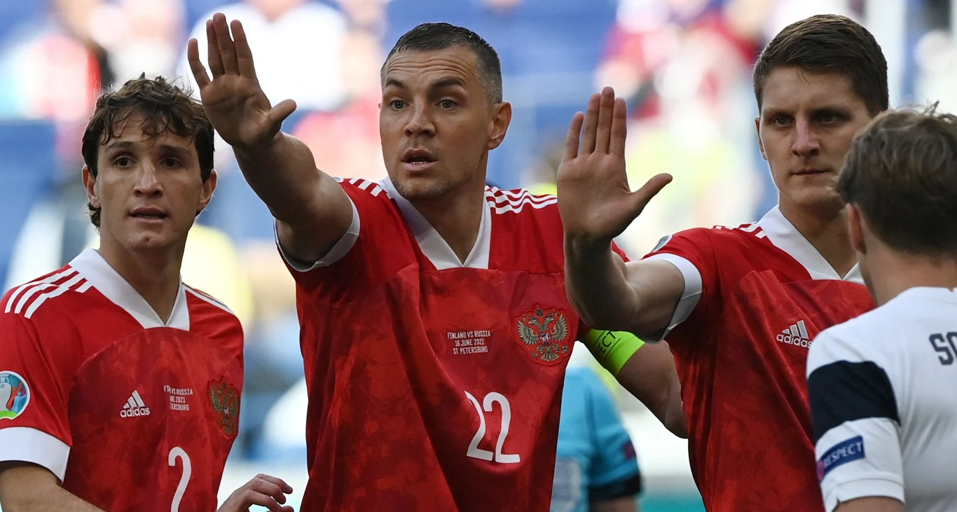 Rozegrane przed czterema laty finały Euro 2020 to jak na razie ostatnia mistrzowska impreza z udziałem reprezentacji Rosji Trzech piłkarzy rosyjskiej reprezentacji w czerwonych koszulkach gestykuluje i komunikuje się na boisku podczas meczu, w tle widać zawodnika przeciwnej drużyny ubranego na biało.