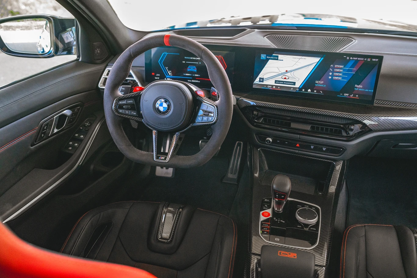 Nowoczesne wnętrze samochodu BMW ze sportową kierownicą, cyfrowym wyświetlaczem i dużym ekranem na desce rozdzielczej, przyciągają uwagę wysokiej jakości wykończeniem oraz nowoczesną technologią.