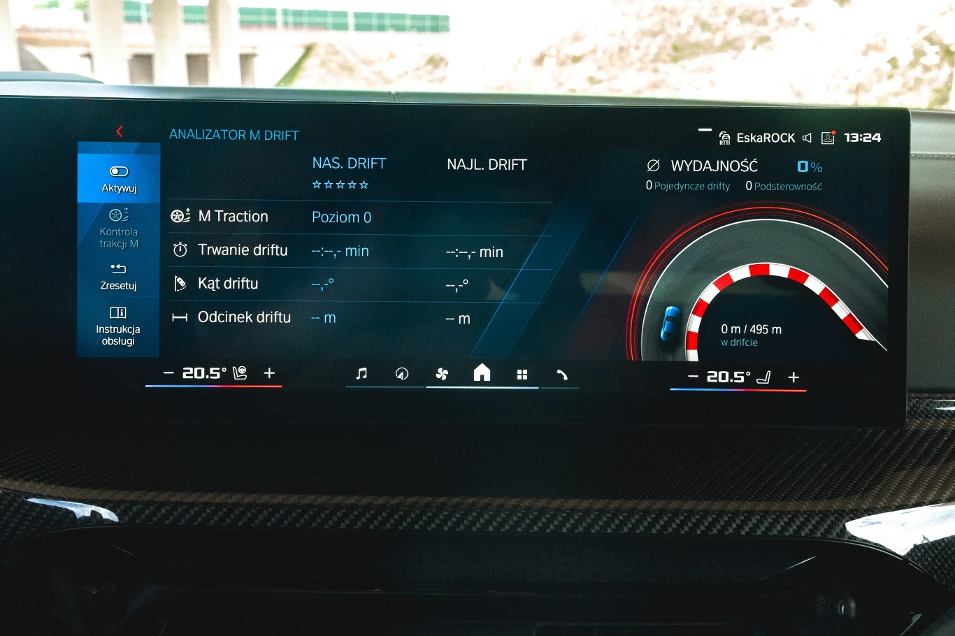 Cyfrowy ekran w samochodzie z menu analizy driftu, wskaźnikiem osiągów, temperaturą oraz informacjami radiowymi, otoczony elementami deski rozdzielczej wykończonej karbonem.