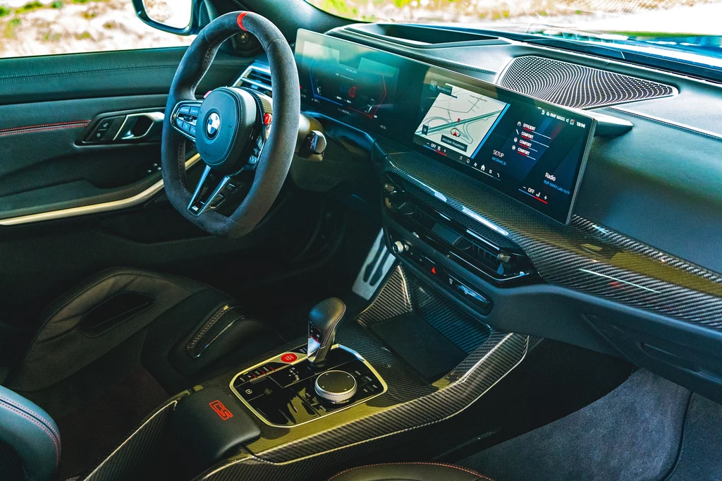 Luksusowe wnętrze nowoczesnego samochodu BMW z cyfrowym panelem sterowania, karbonowymi wykończeniami, sportową kierownicą oraz wyświetlaczem nawigacji GPS.